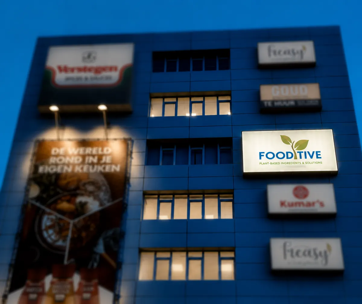 Fooditive’s first office in Rotterdam: a blue office building at dusk with the Fooditive sign among other company signs