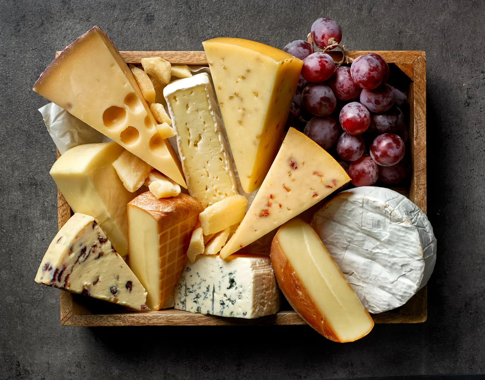 A board of assorted cheeses with grapes