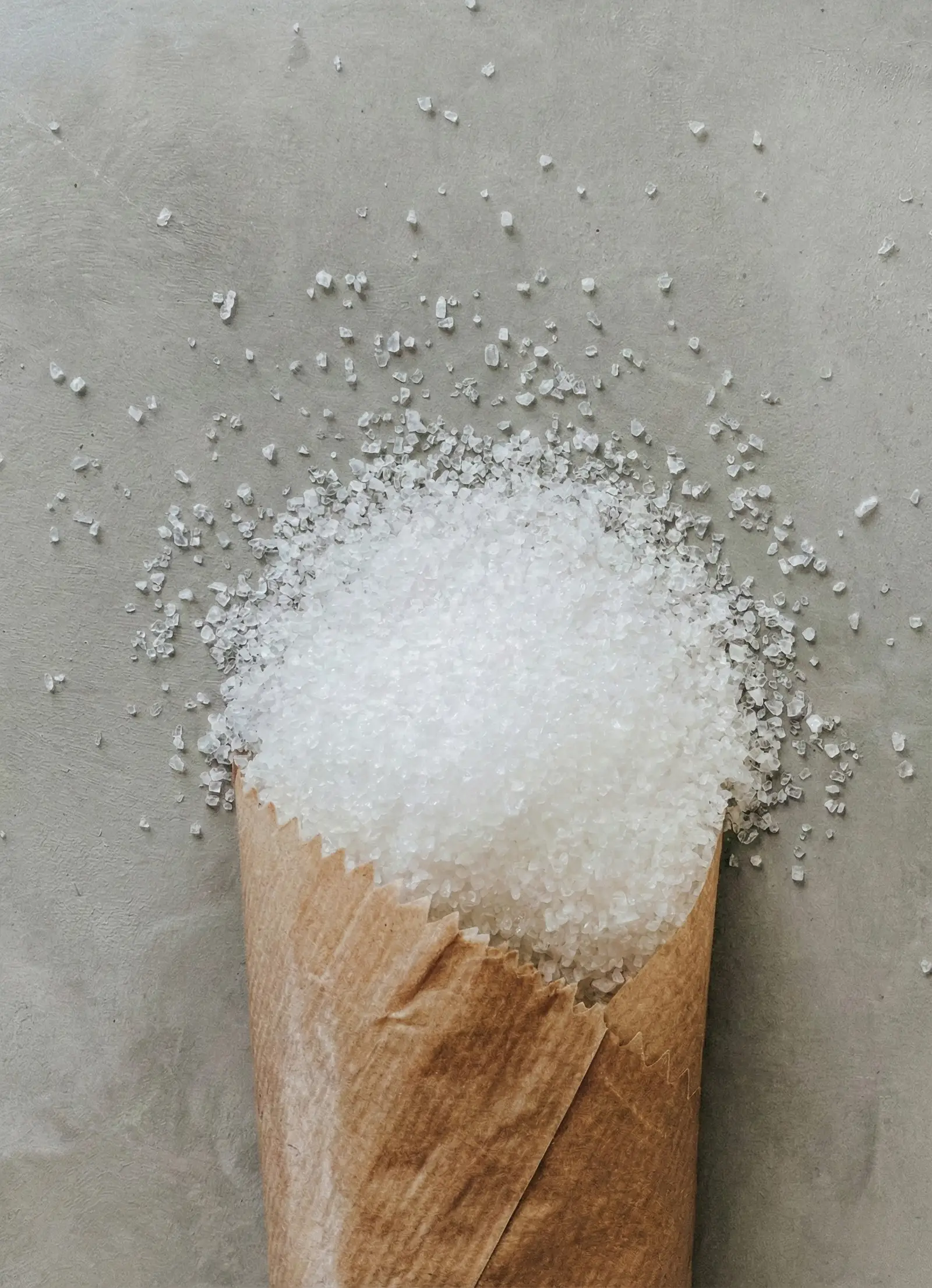 White salt crystals spilling from a paper bag