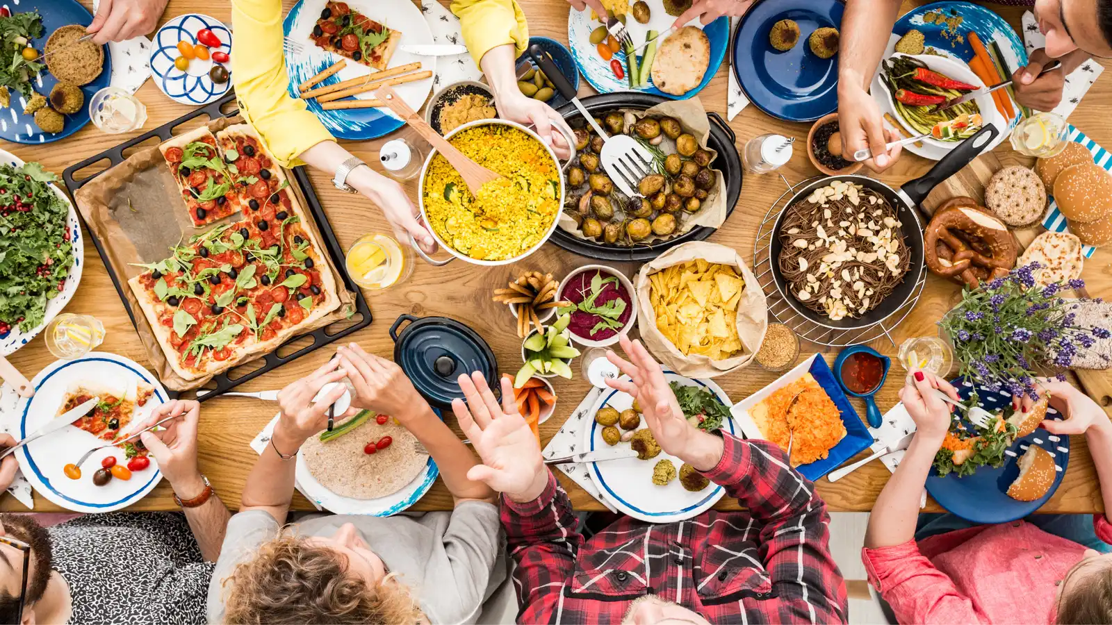 People sharing many dishes around a long table, seen from above