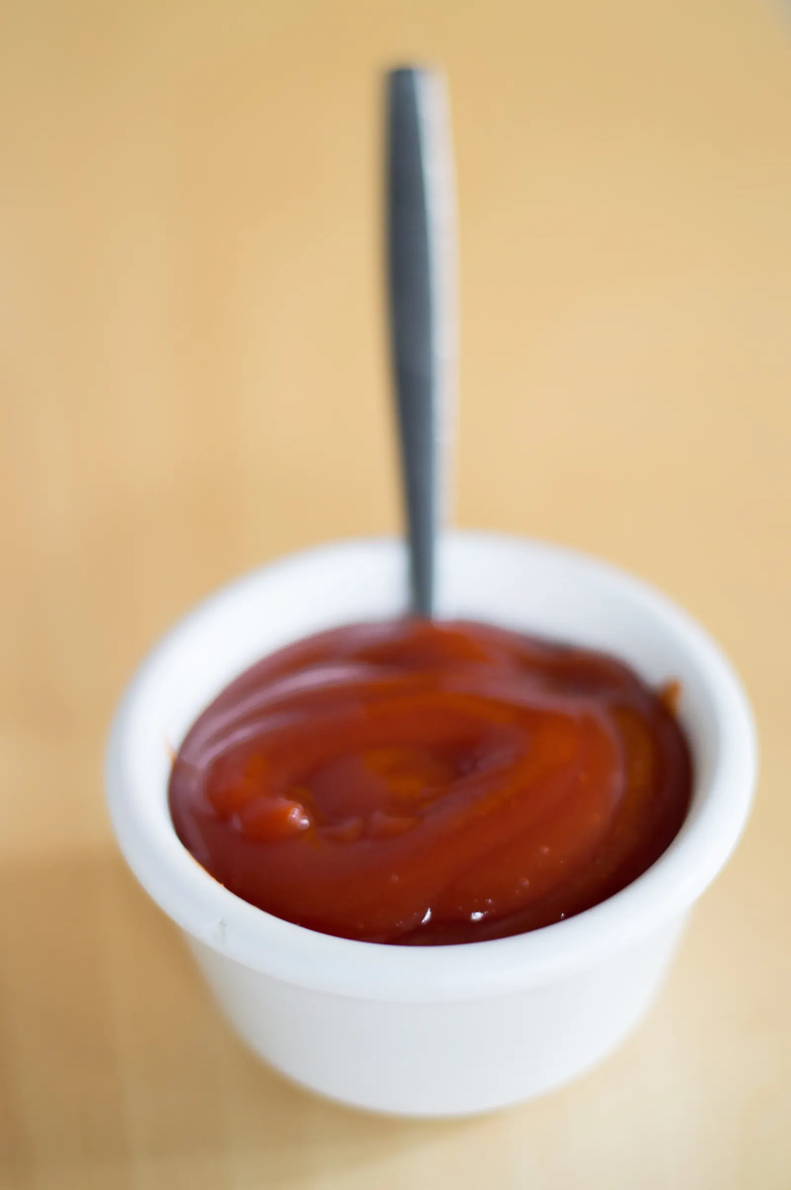 A spoon lifting red sauce from a white bowl